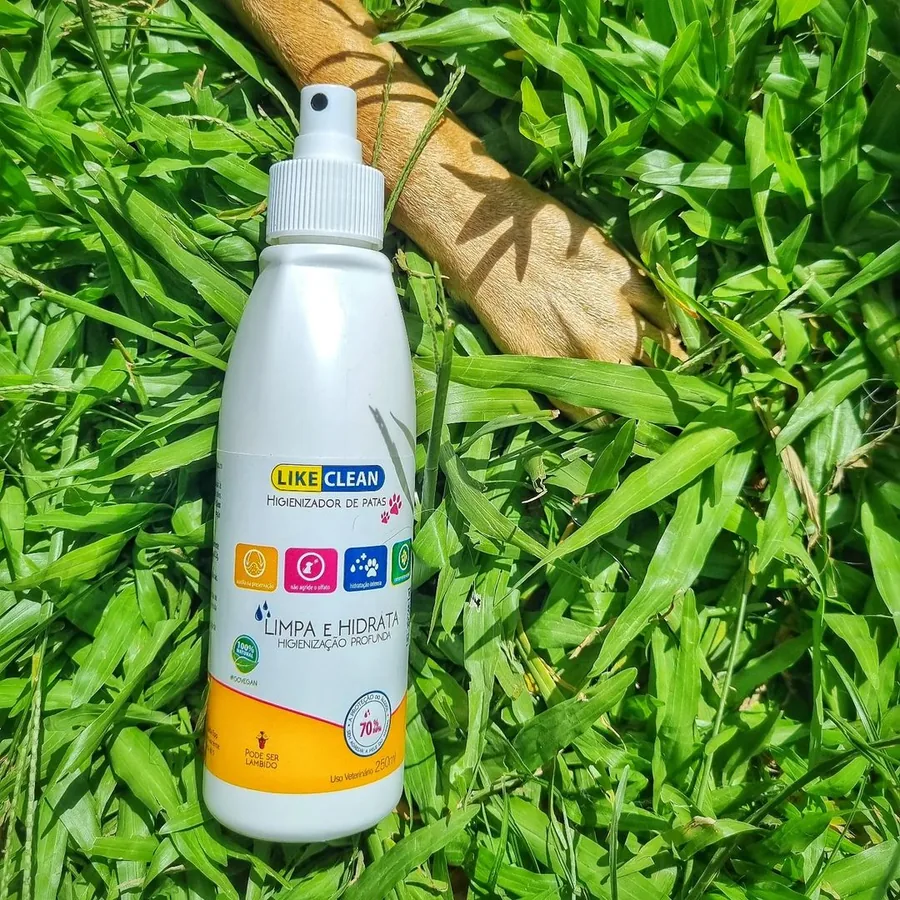 Frasco de 250 ml do Like Clean sobre a grama, ao lado da pata de um cão